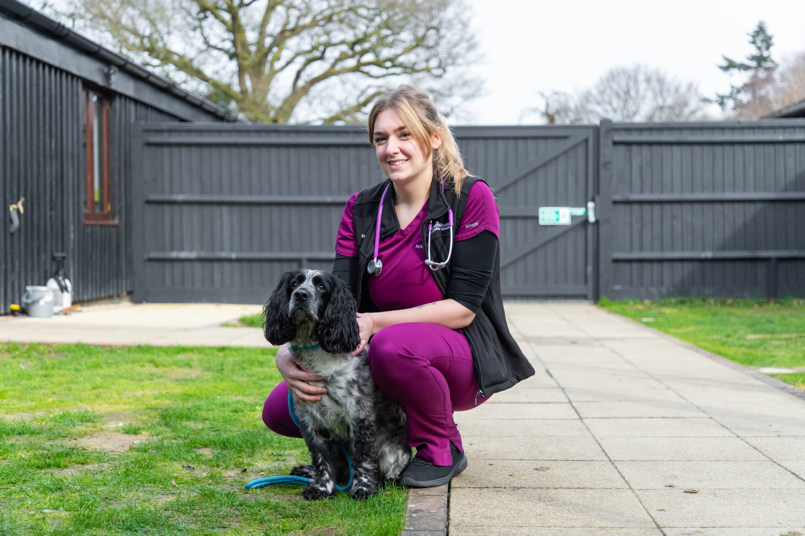 Vet sitting with a black and grey dog in a garden area