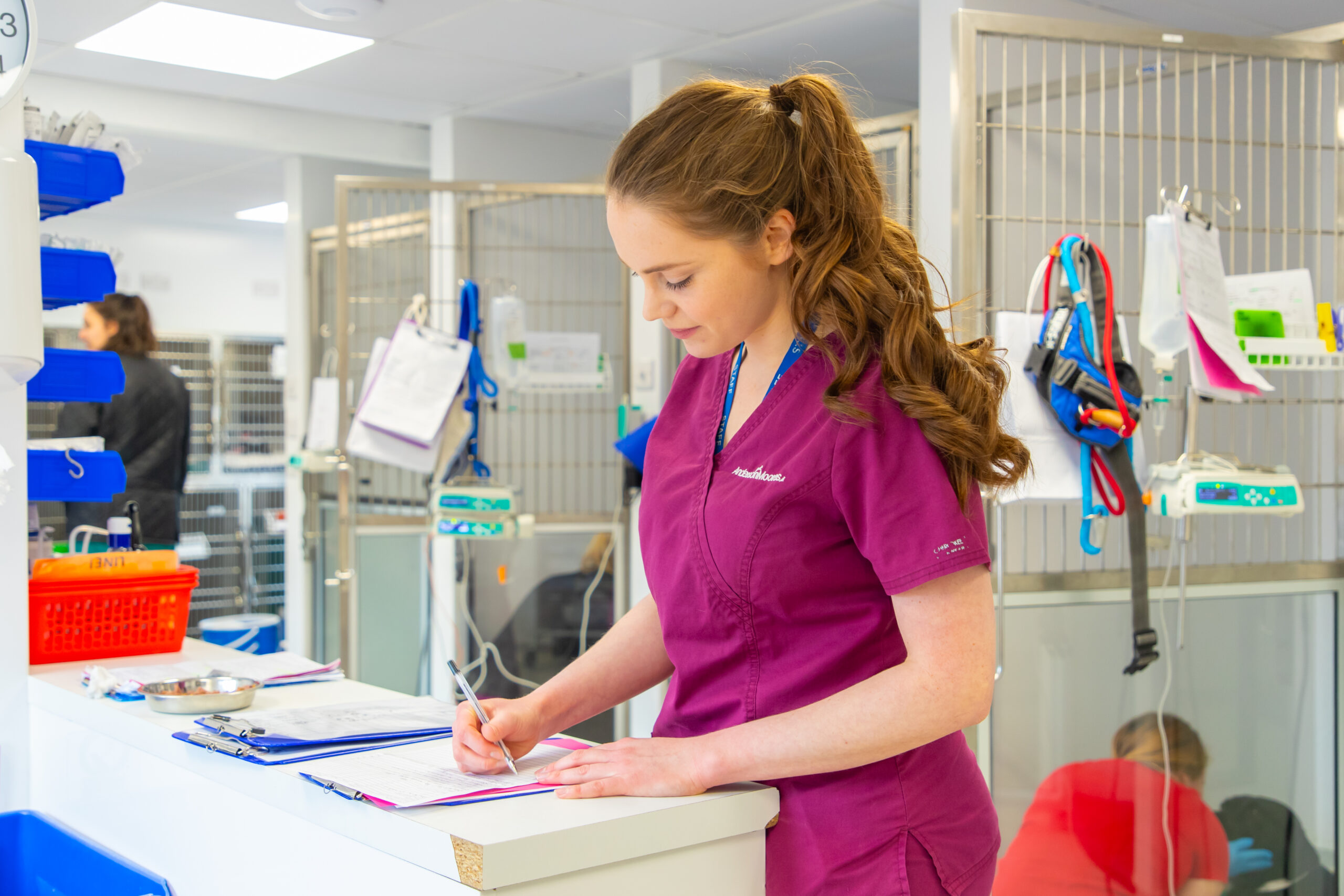 female vet standing writing on a document in a medical facility