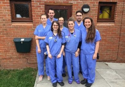 group of veterinary staff standing in scrubs outside of a building